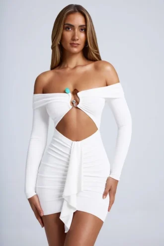 Saffron minijurk met hardware-details, off-shoulder en uitsnijdingen in wit